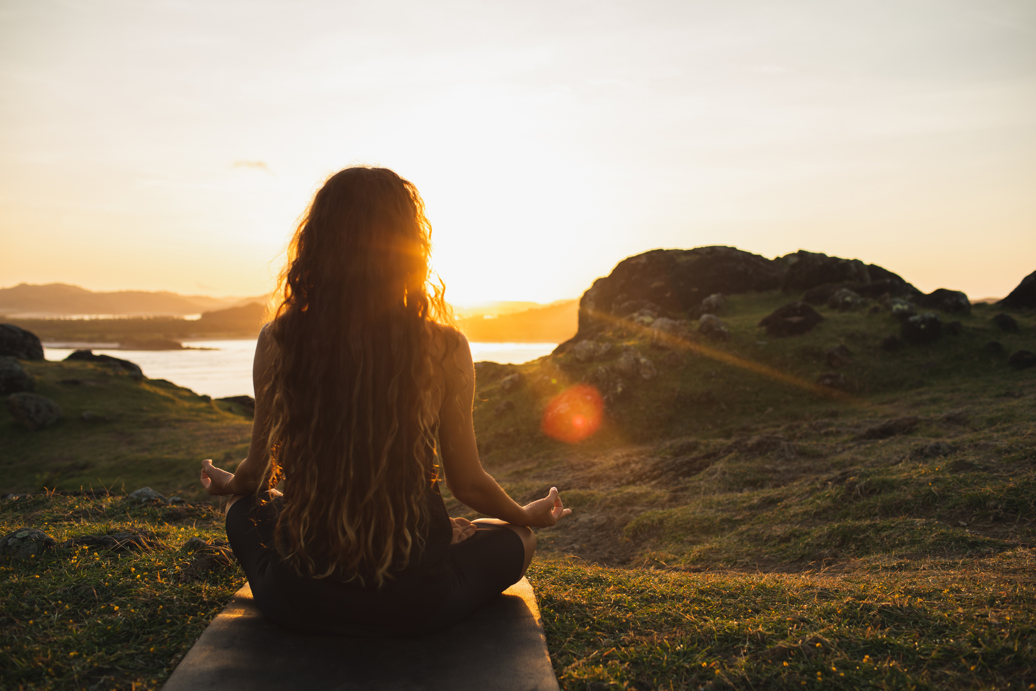 Woman meditating yoga alone at sunrise mountains. View from behind. Travel Lifestyle spiritual relaxation concept. Harmony with nature.