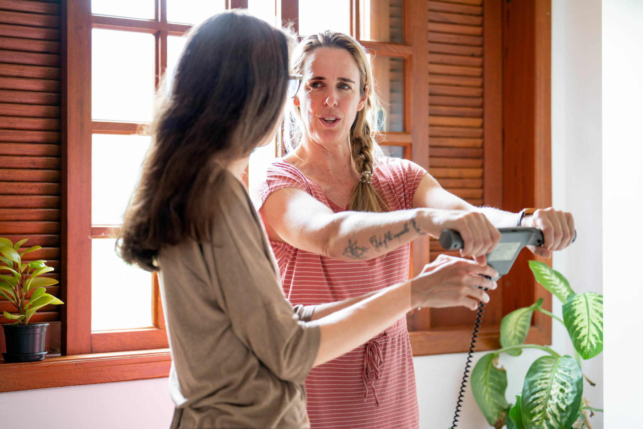 Female nutritionist speaking with a client using a body composition monitor and scale during a consultation in her home office