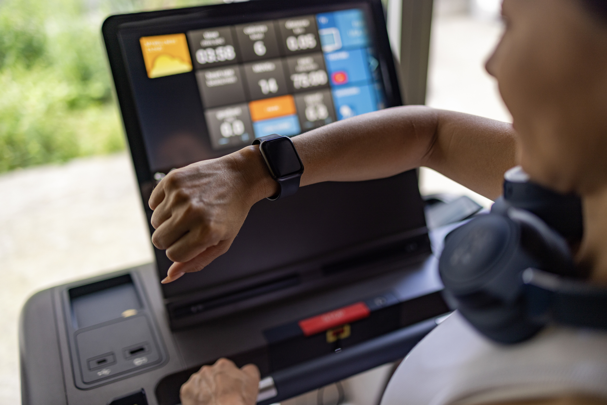 Close up of unrecognizable athletic woman tracking her health on smartwatch during sports training on treadmill in a gym.
